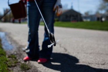 A volunteer holds a used syringe found a long a ditch line on Church St. in Austin, Indiana on April 11,2015. (Photo by Seth Herald/NurPhoto via AP Images)