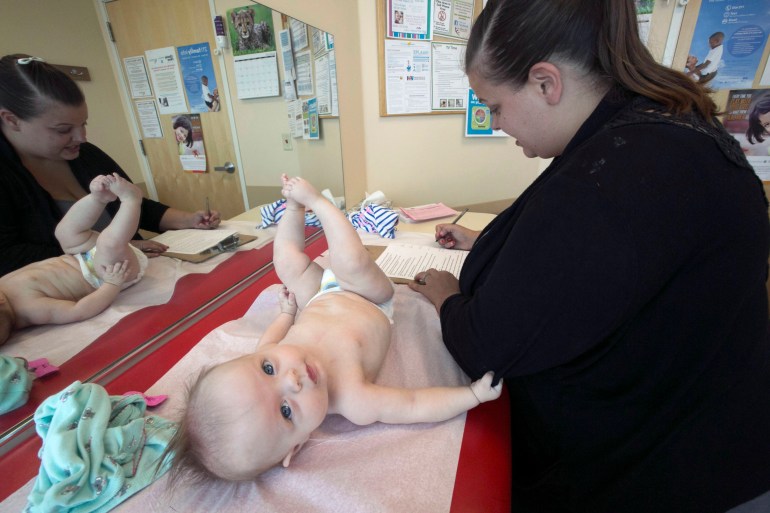 Payton Pike kicks her feet as her mother Sarah Pike fills out a survey during Payton's four-month-old exam at The Children's Clinic in Portland, September 3, 2015 (Kristyna Wentz-Graff/ The Oregonian).