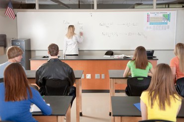 A rear view image of a high school classroom with teenagers learning science and chemistry.