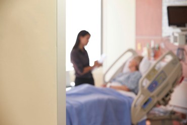 Focus On Hospital Room Sign With Doctor Talking To Patient