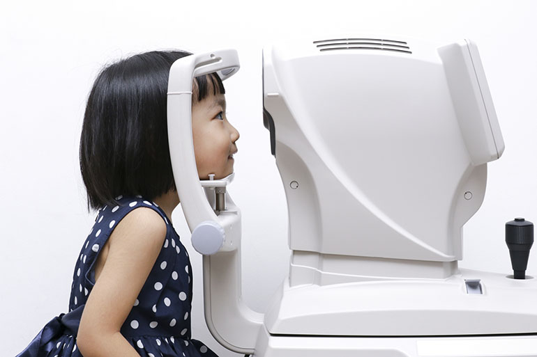Asian Little Chinese Girl Doing Eyes Examination Through Auto refraktometer in isolated White Background