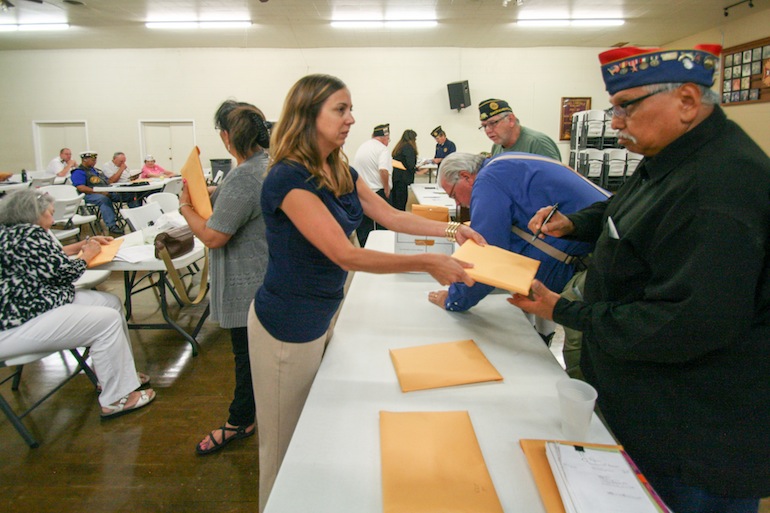Meghan Callahan hands out envelopes of No on 61 campaign materials to veterans at a Sacramento Veterans Affiliated Council meeting on Sept. 1, 2016. Callahan works for a media relations firm paid by the campaign, which has received more than $86 million dollars from pharmaceutical companies. (Pauline Bartolone/California Healthline)