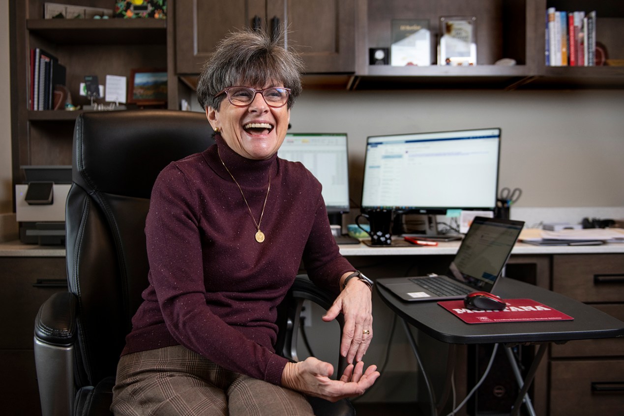 Photo of Marilyn Bartlett sitting at her desk smiling