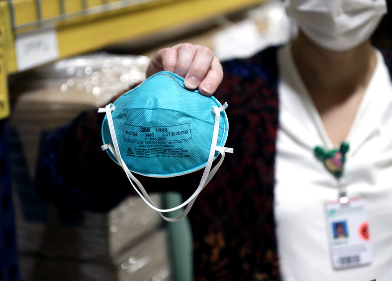 A masked woman holds an N95 mask