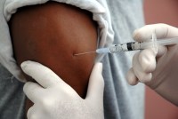 A vaccine shot is administered to a man's arm
