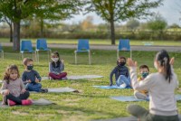 Diverse group of students sitting outside on yoga mats while wearing protective face masks during the COVID-19 pandemic.