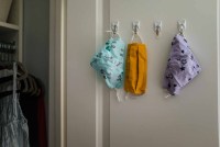 three cloth masks hanging on hooks in closet