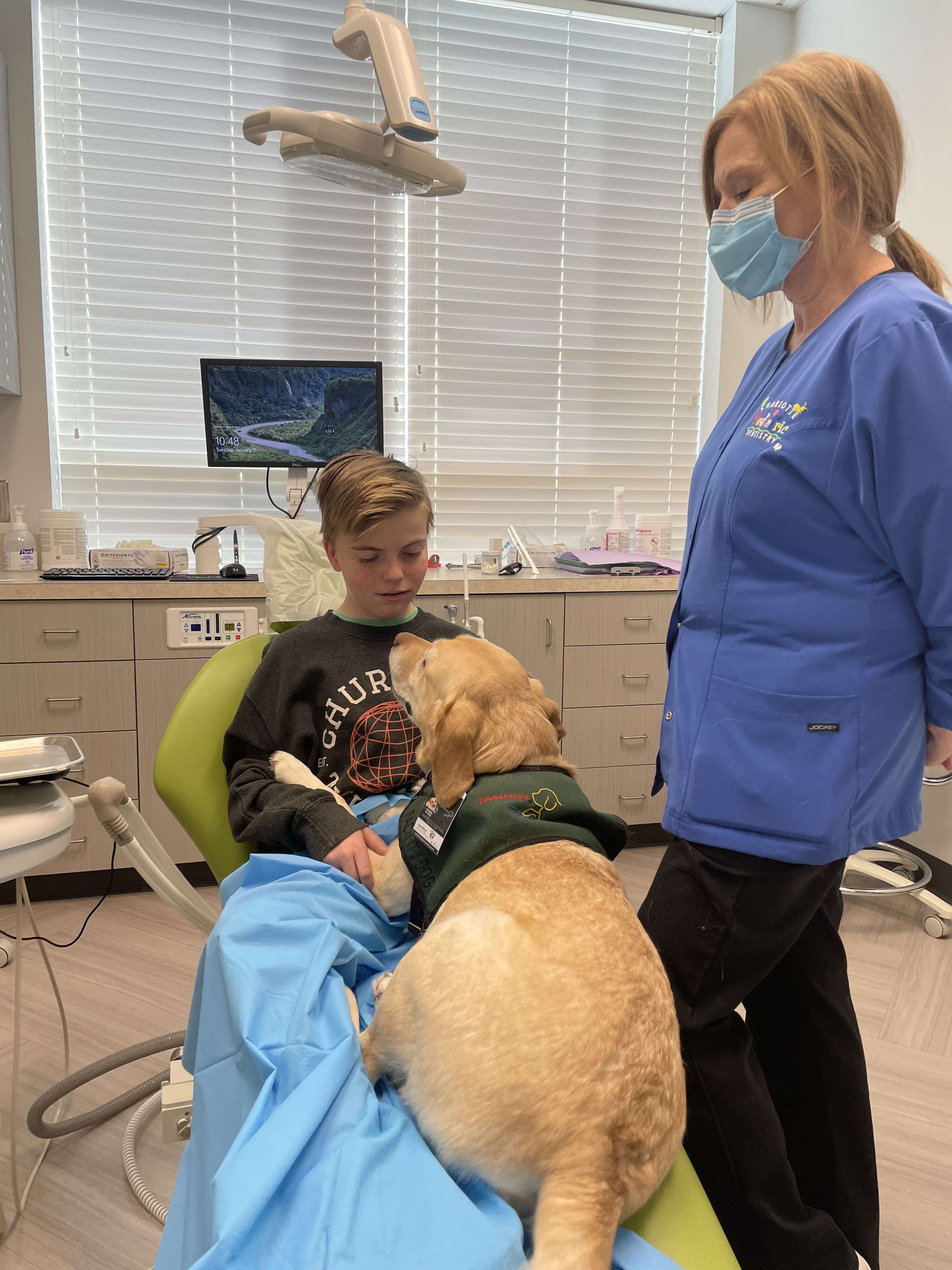 Levi McAllister looks down at Atkins, the Labrador retriever who sat in his lap while getting his teeth pulled.