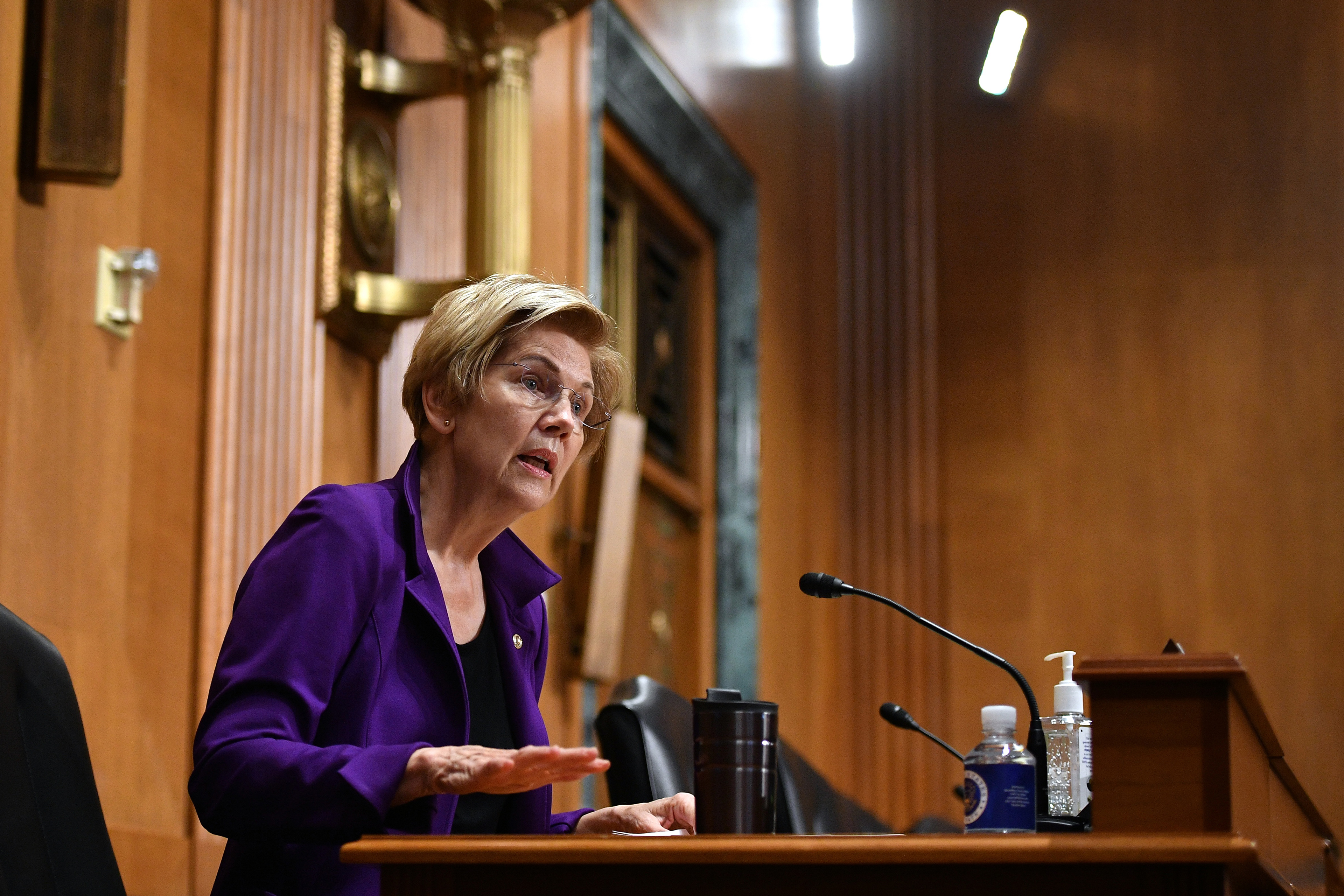 Sen. Elizabeth Warren is seen facing to the right, speaking into a microphone during a Senate Finance Committee hearing.