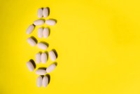 A photo shows pills arranged in the shape of a dollar sign on a bright yellow surface.