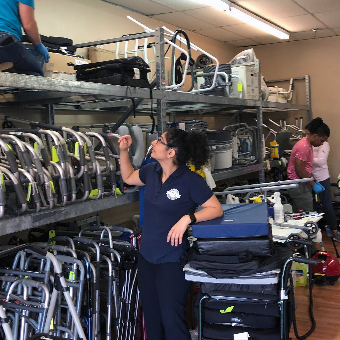 a woman wearing scrubs looks at rows of walkers and wheelchairs