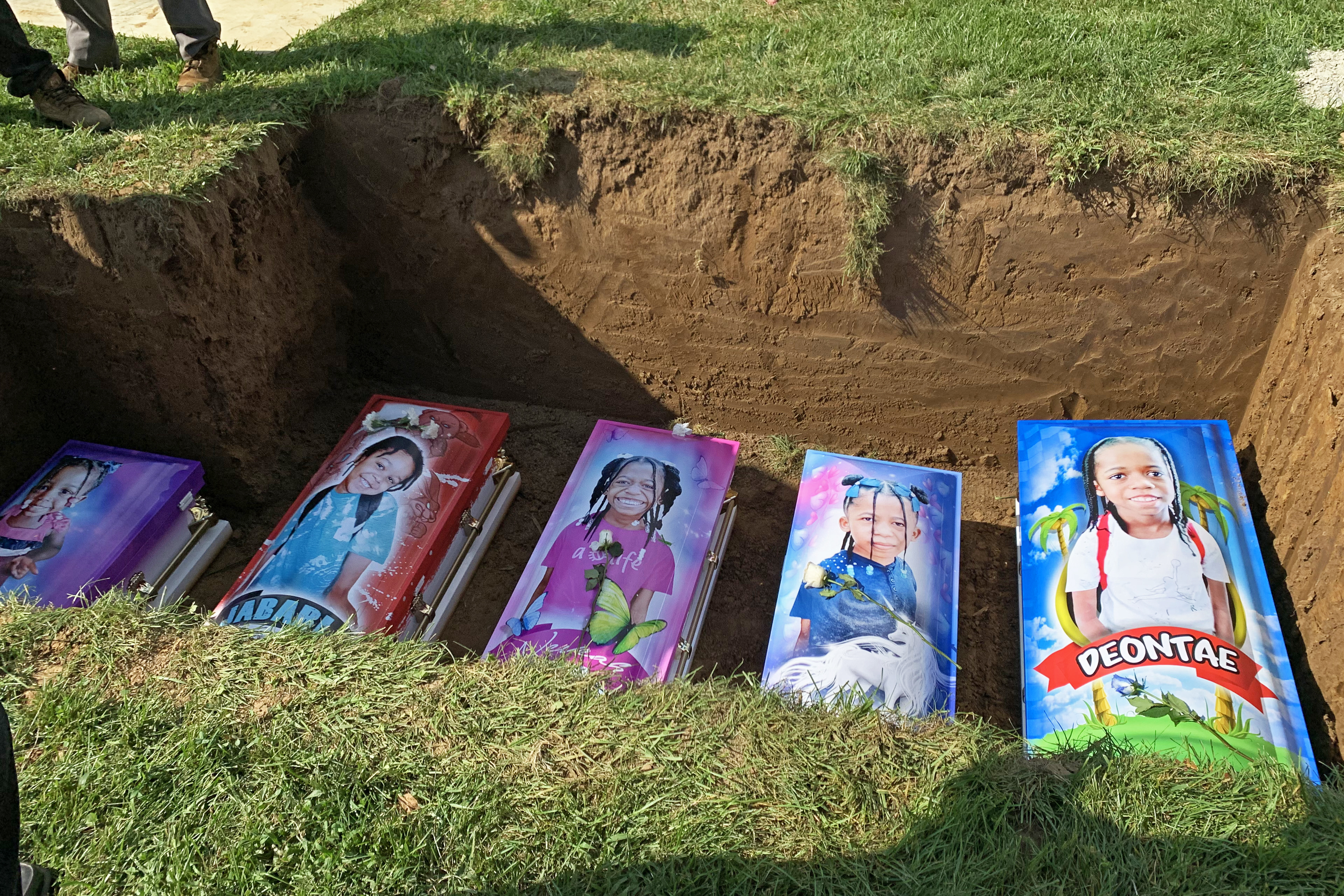 Peti mati lima anak tergeletak di tanah, dicetak dengan gambar diri mereka sendiri dan warna-warna cerah.