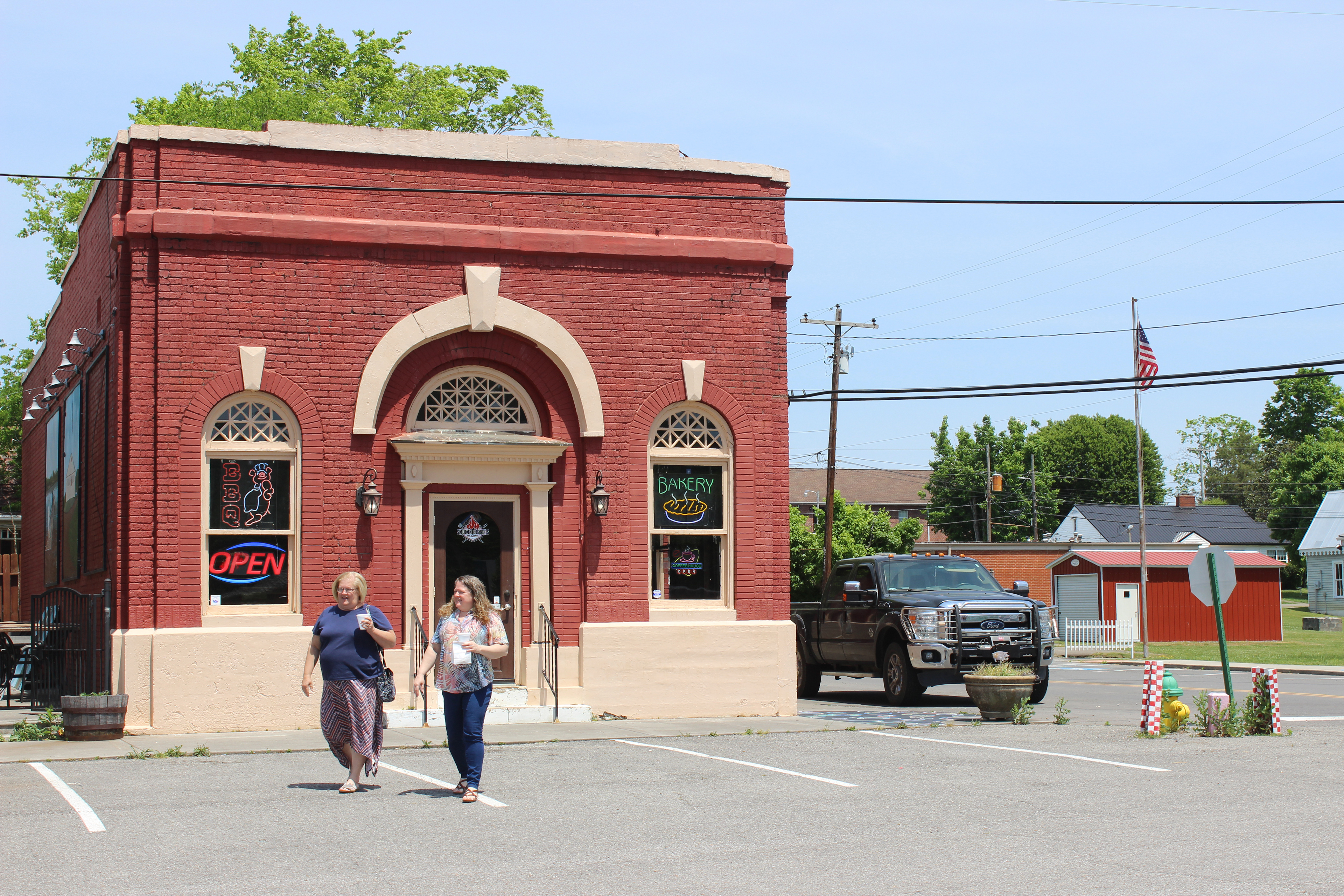 Güneşli bir günde Decatur, Tennessee'de iki kişi bir binanın önünden geçiyor.