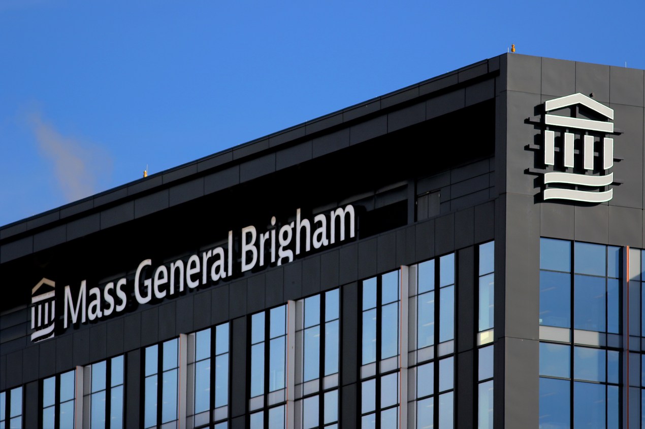 The exterior facade of an office building shows the name, "Mass General Brigham" along with the company's logo.