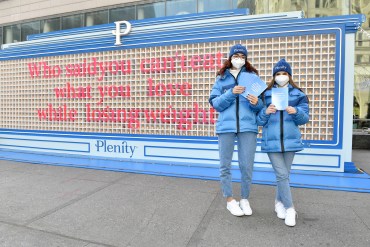 A photo shows two Plenity representatives holding flyers in front of an edible billboard that reads, "Who said you can't eat what you love while losing weight?"