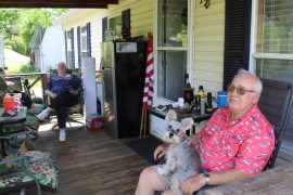 Fletcher and Brenda Letner are seen sitting on their porch. Their dog, Hazzy, sits on Fletcher's lap.