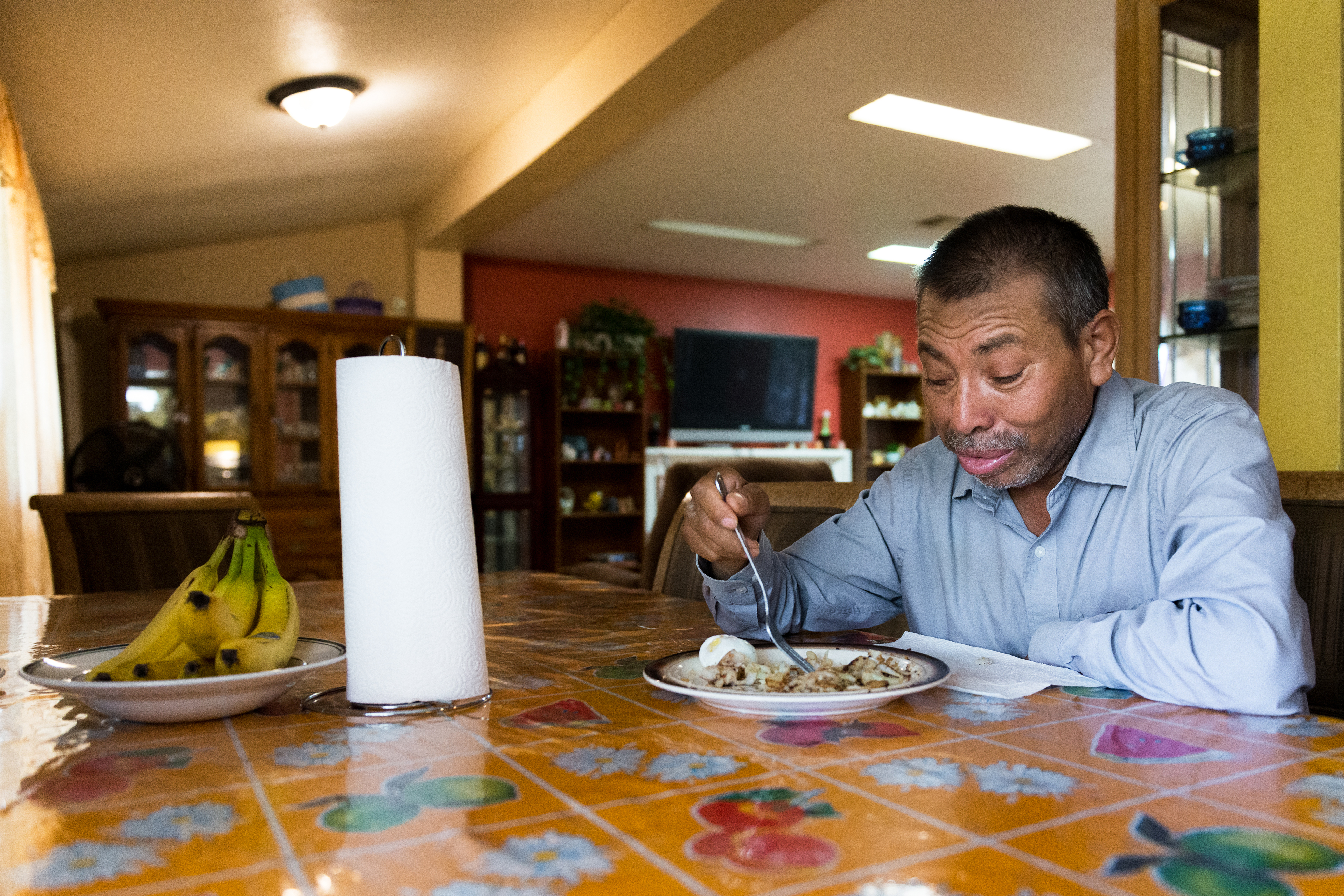 Vidal Fonseca terlihat sedang makan di sebuah meja di rumahnya.  Gulungan handuk kertas dan sepiring pisang juga ada di atas meja.