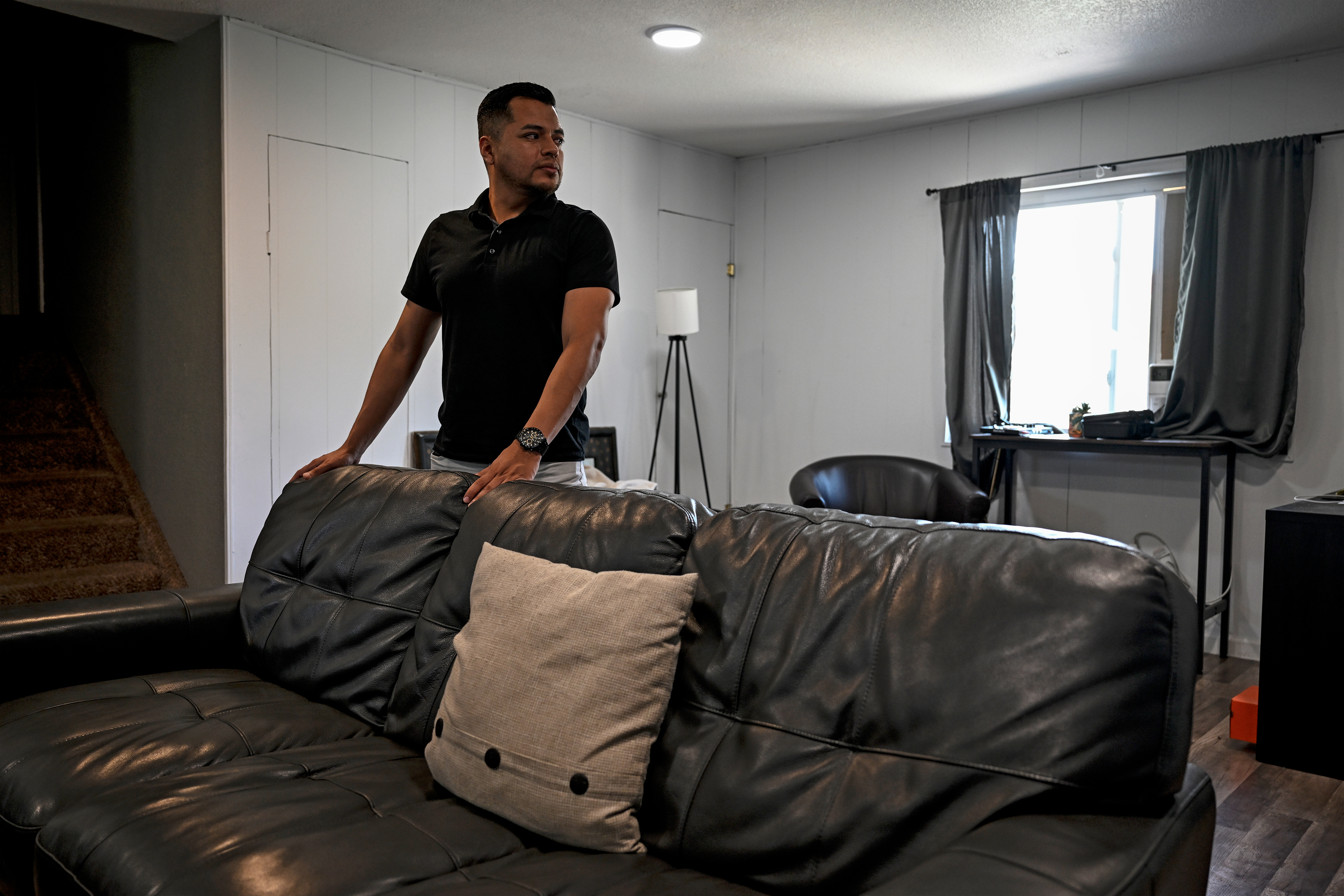 A photo shows Armando Peniche Rosales standing by a couch at home.