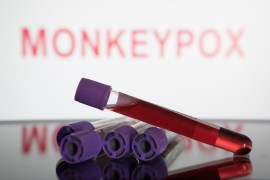 A photo illustration shows blood test vials on a table. Behind them, red text reads, "Monkeypox."