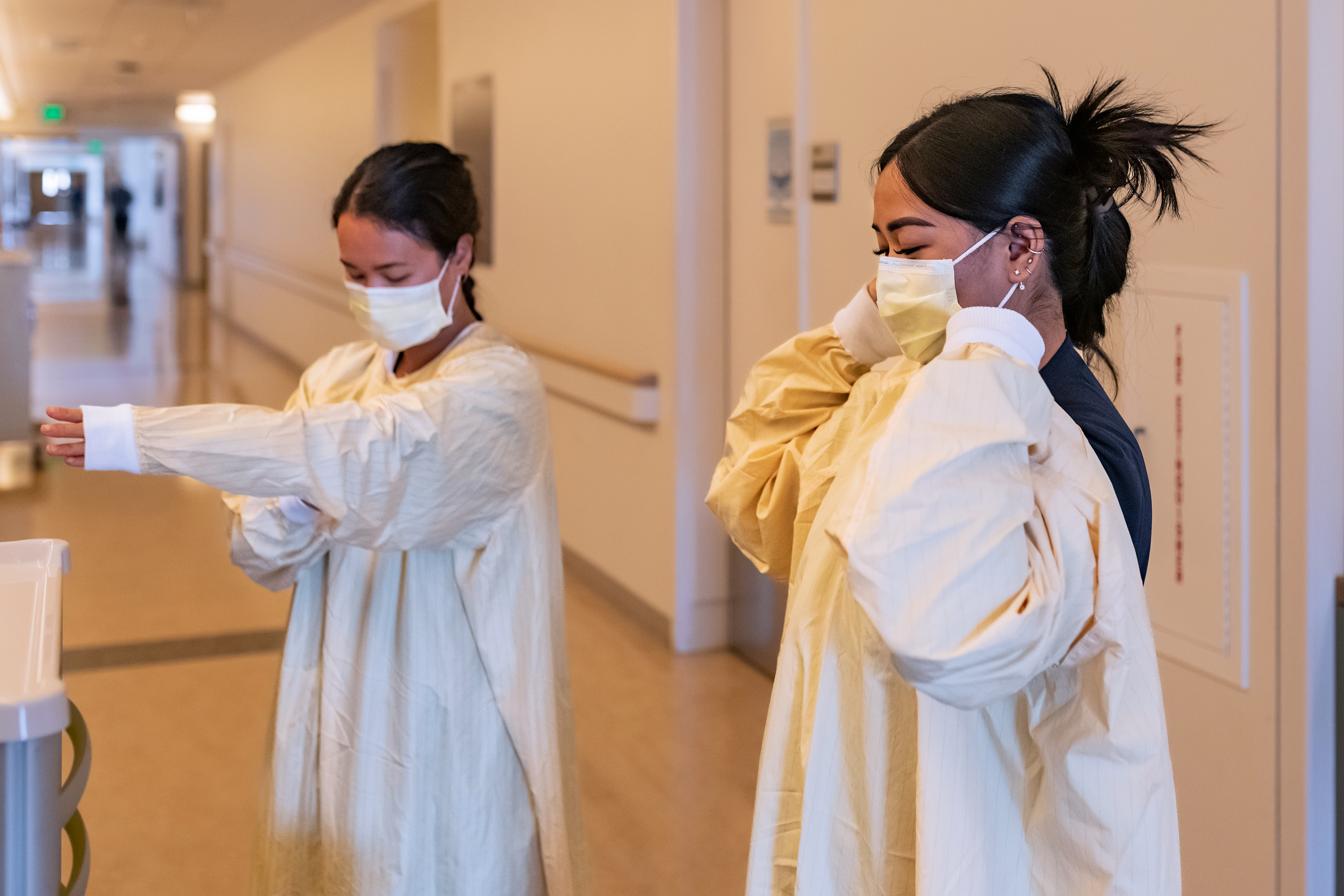 Bir fotoğraf, bir tıp merkezinin içinde yeniden kullanılabilir izolasyon önlükleri giyen iki hemşireyi gösteriyor.
