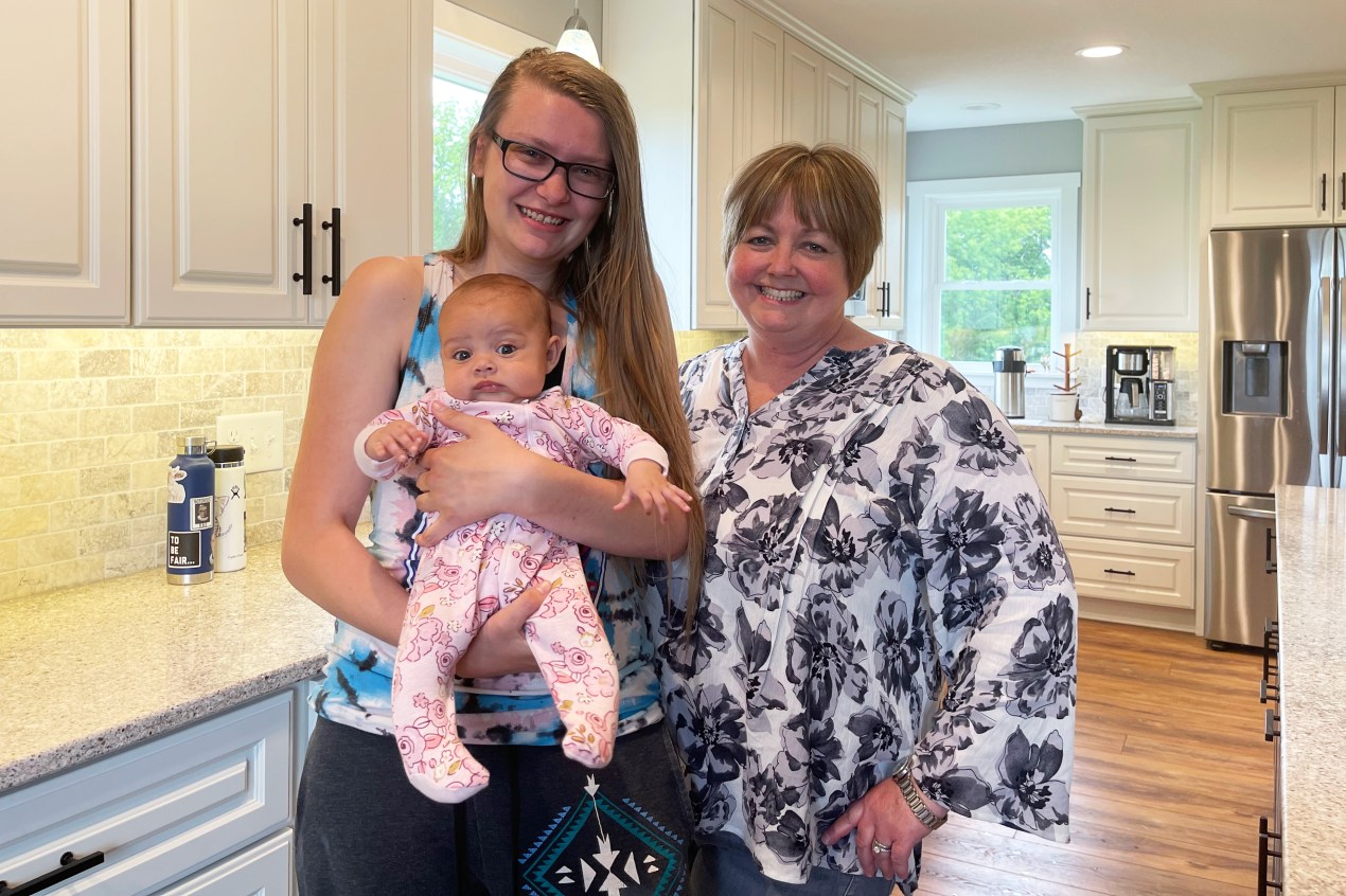 A photo shows Jennifer Magee and Geralyn Laurie standing next to each other at home. Magee is holding her daughter, Aubrey.
