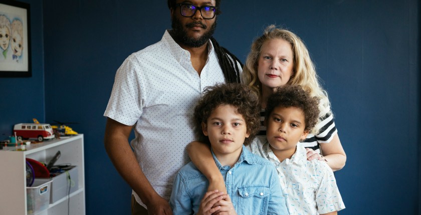 A family stands together in a room painted dark blue.