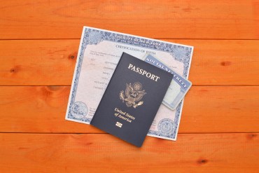 A photo shows a passport, social security card and a birth certificate on a table.