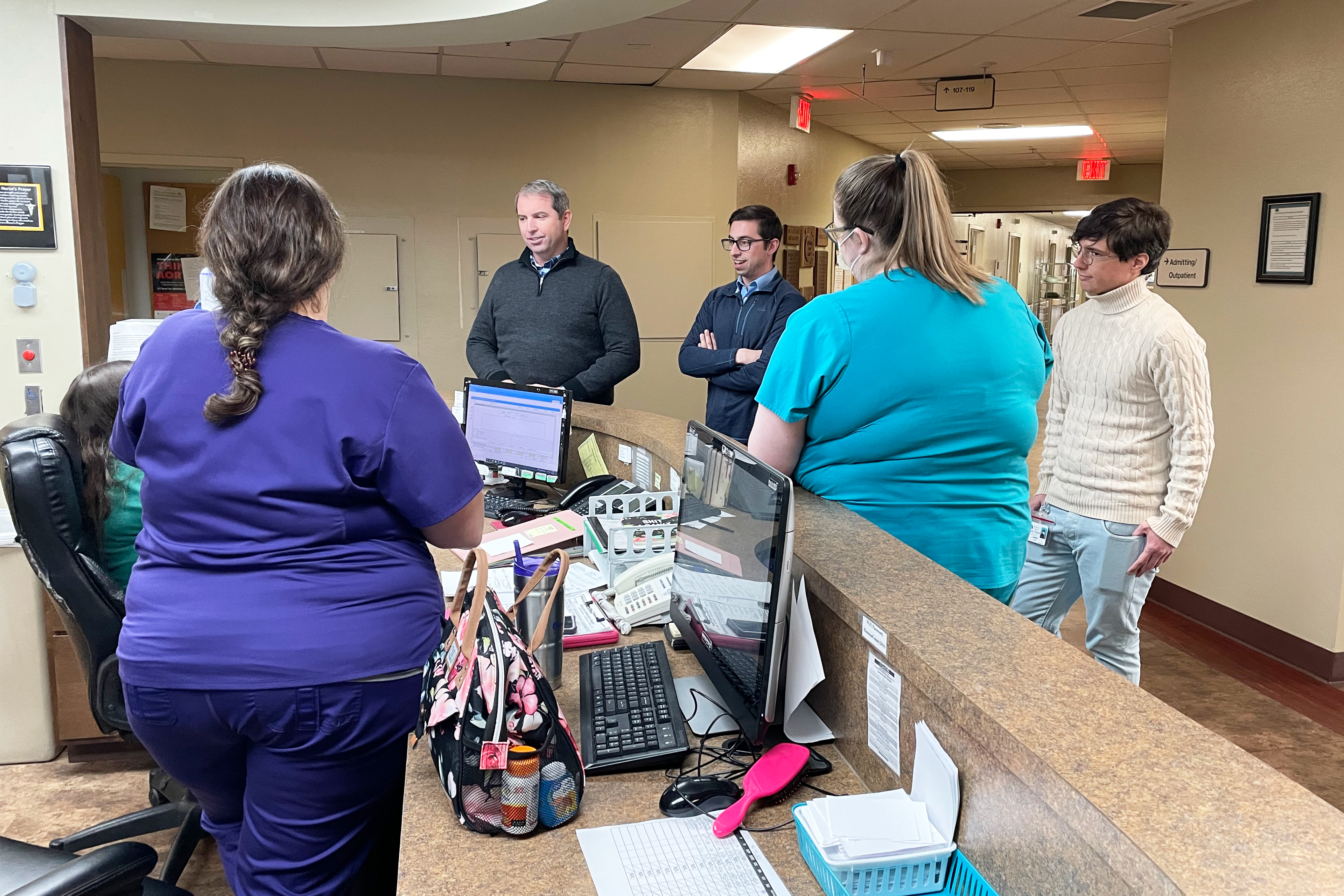 A photo shows staff gathered around the front desk of a hospital waiting room.