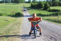 A photo shows Mason Lester riding a bike down a country road. A white car is seen on the road in the distance.