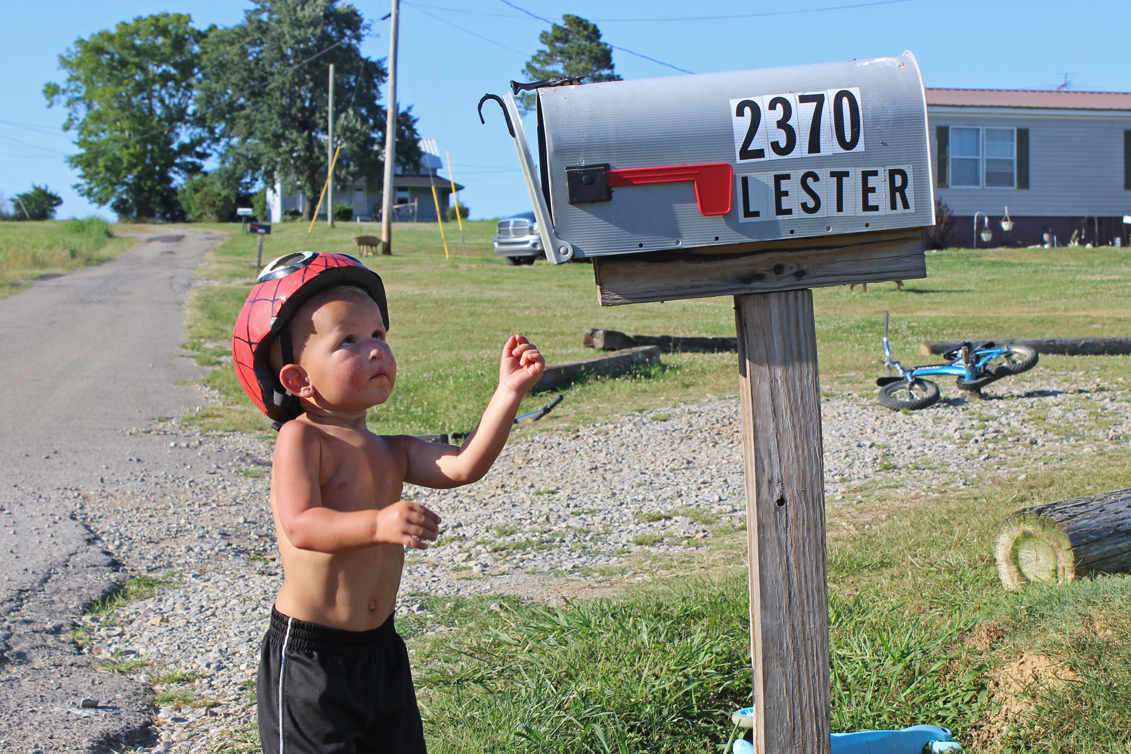 A photo shows Memphis Lester looking up at a mailbox. The mailbox has the house numbers and family's name on it.