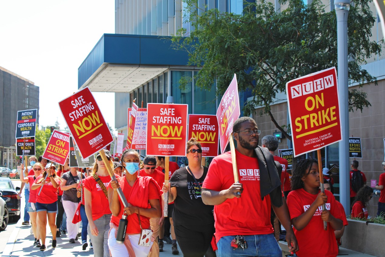 A photo shows picketers holding signs outside of the Kaiser Permanente hospital in Oakland, California.