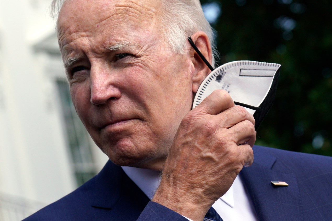 A close-up photo shows President Biden taking a KN-95 mask off of his face.