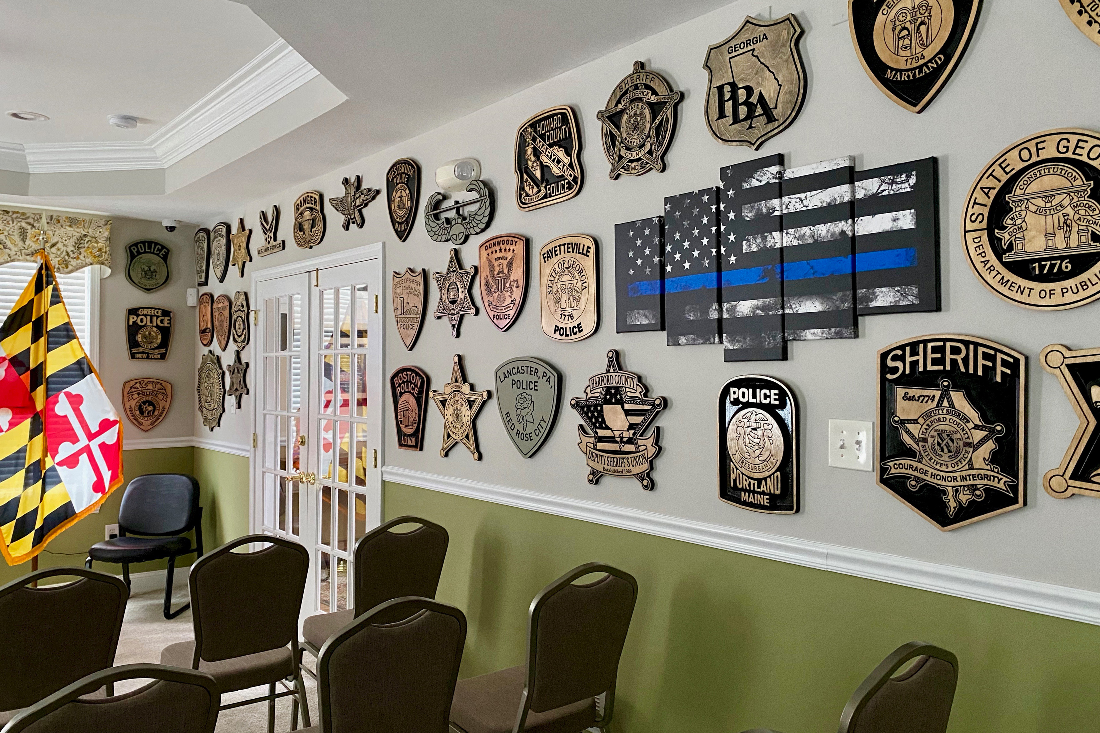 Bir fotoğraf, kolluk kuvvetlerine adanmış plaklarla süslenmiş, sıra sıra sandalyeler ve duvarları olan bir odayı göstermektedir.