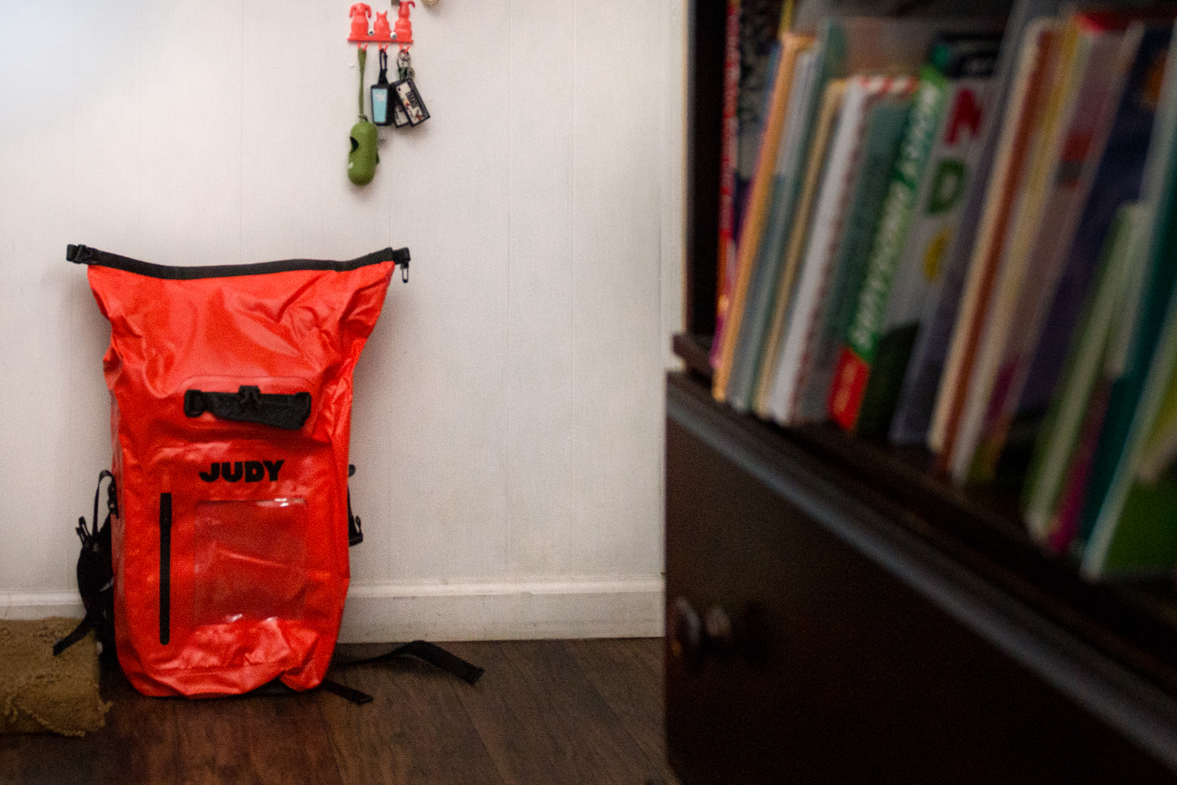 A photo shows a bright orange "go bag" resting on a wall inside.