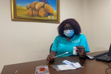 A photo shows Valentine Cesar holding an HPV self-testing swab.