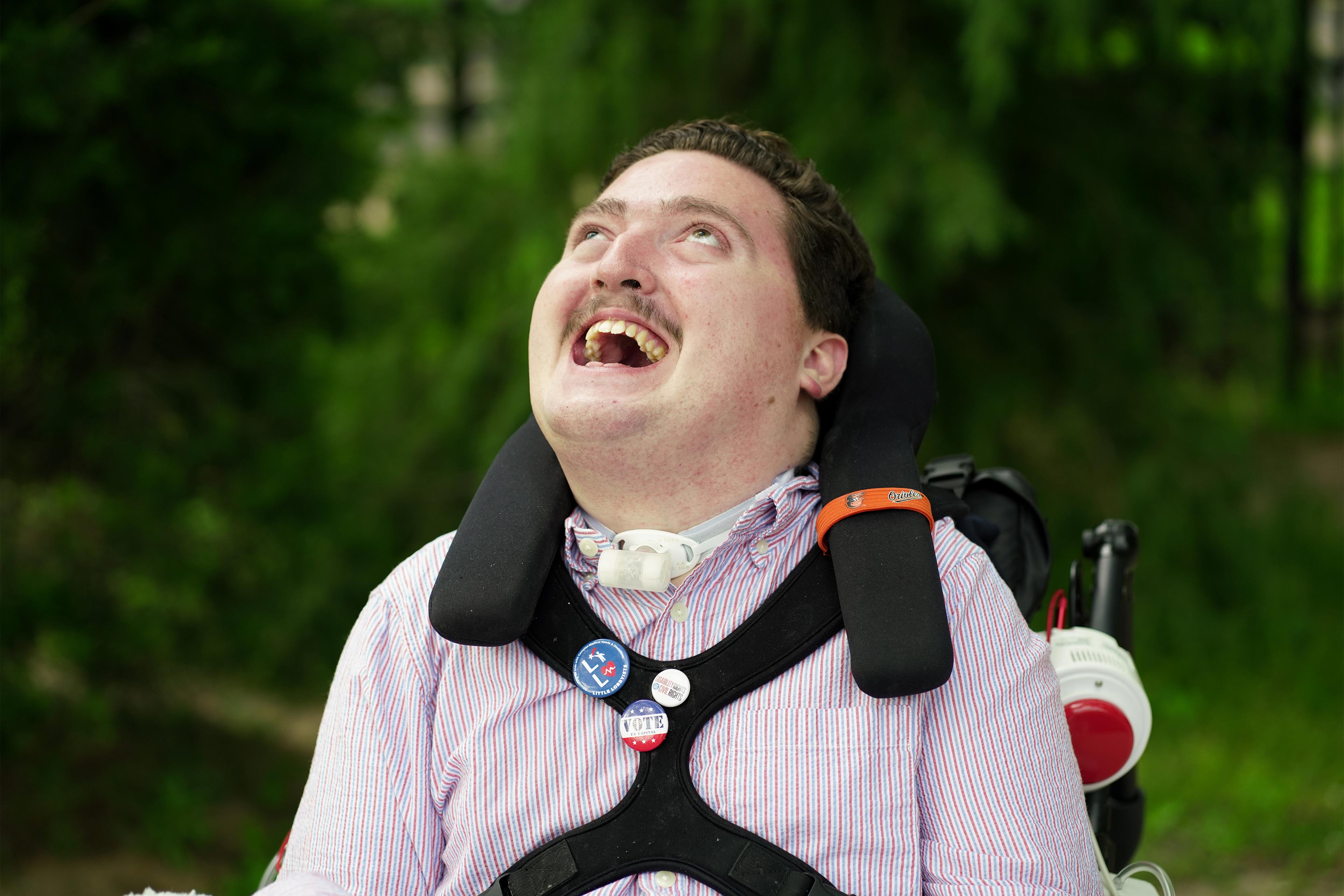 Bir fotoğraf, Rob Stone'un dışarıda bir portre için poz verdiğini gösteriyor.  Tekerlekli sandalyede oturuyor.