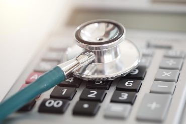 A photo shows a doctor's stethoscope over a calculator.