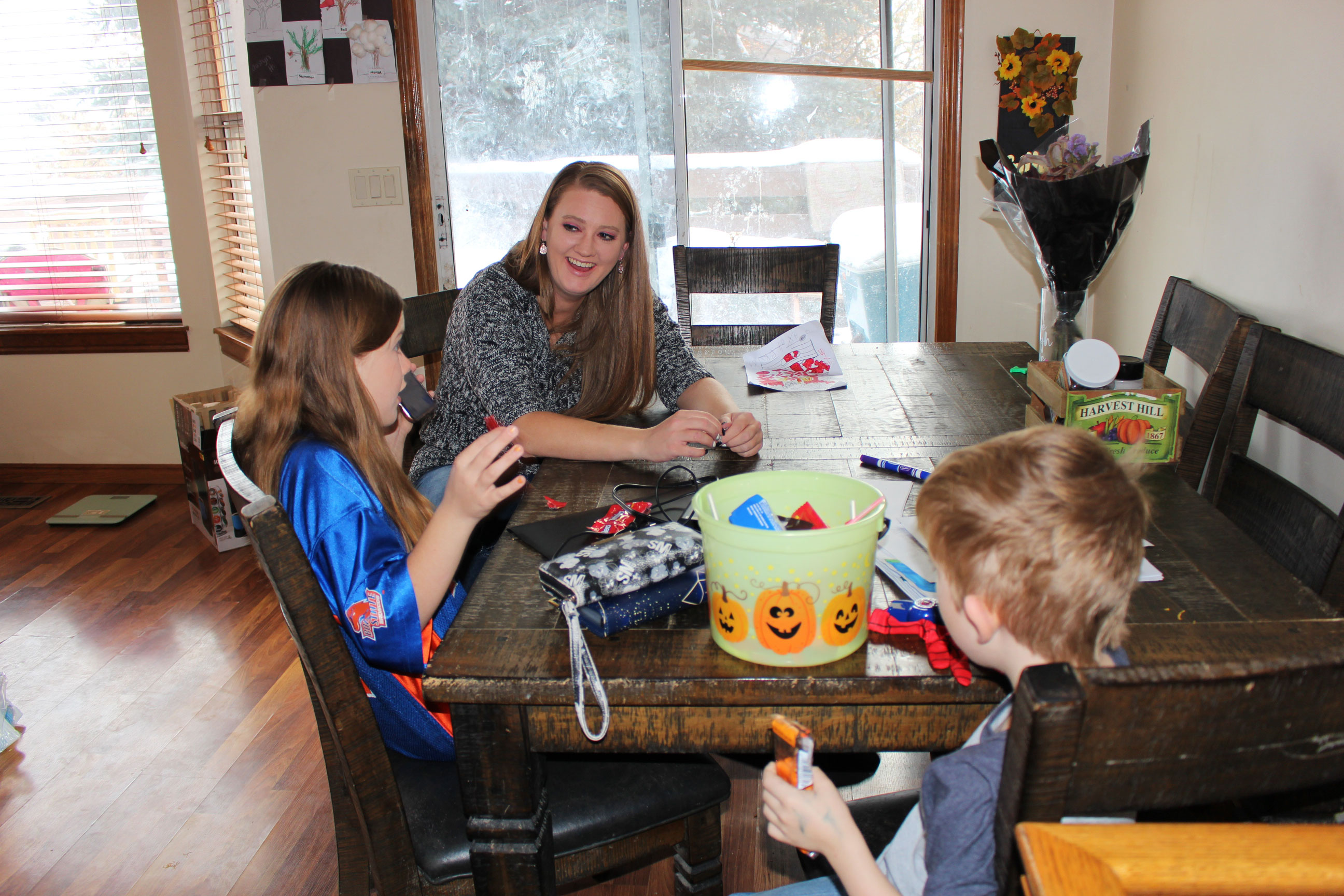 Bir fotoğraf, Kayla Hopkins'i çocuklarıyla birlikte evde gösteriyor.  Bir masada oturuyorlar.