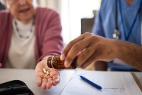 A photo shows a medical professional helping a senior woman with her pills.