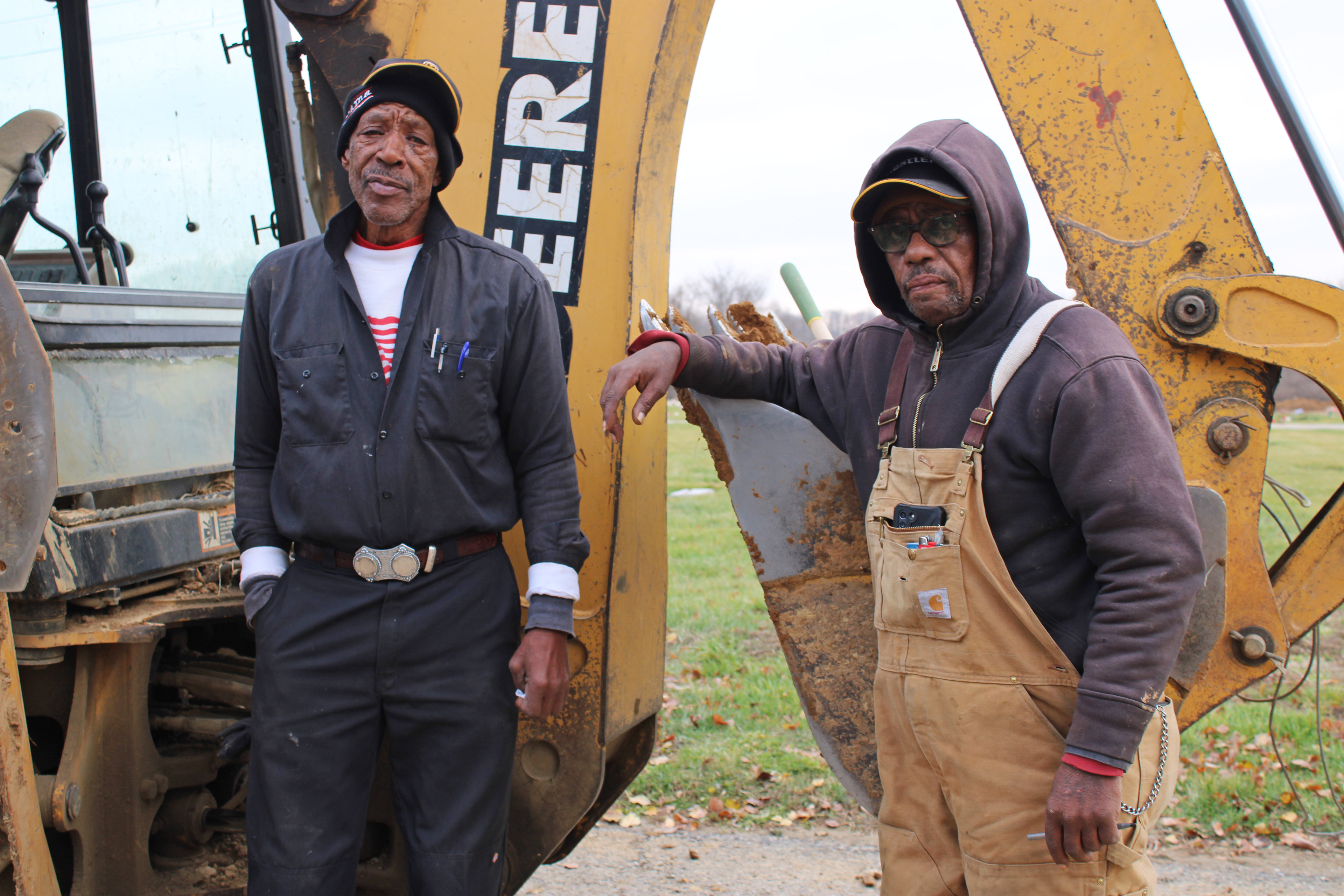 A photo shows Johnnie Haire and William Belt Sr. posing for a photo together in front of an excavator.