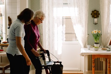 A photo shows a caregiver helping an elderly woman.