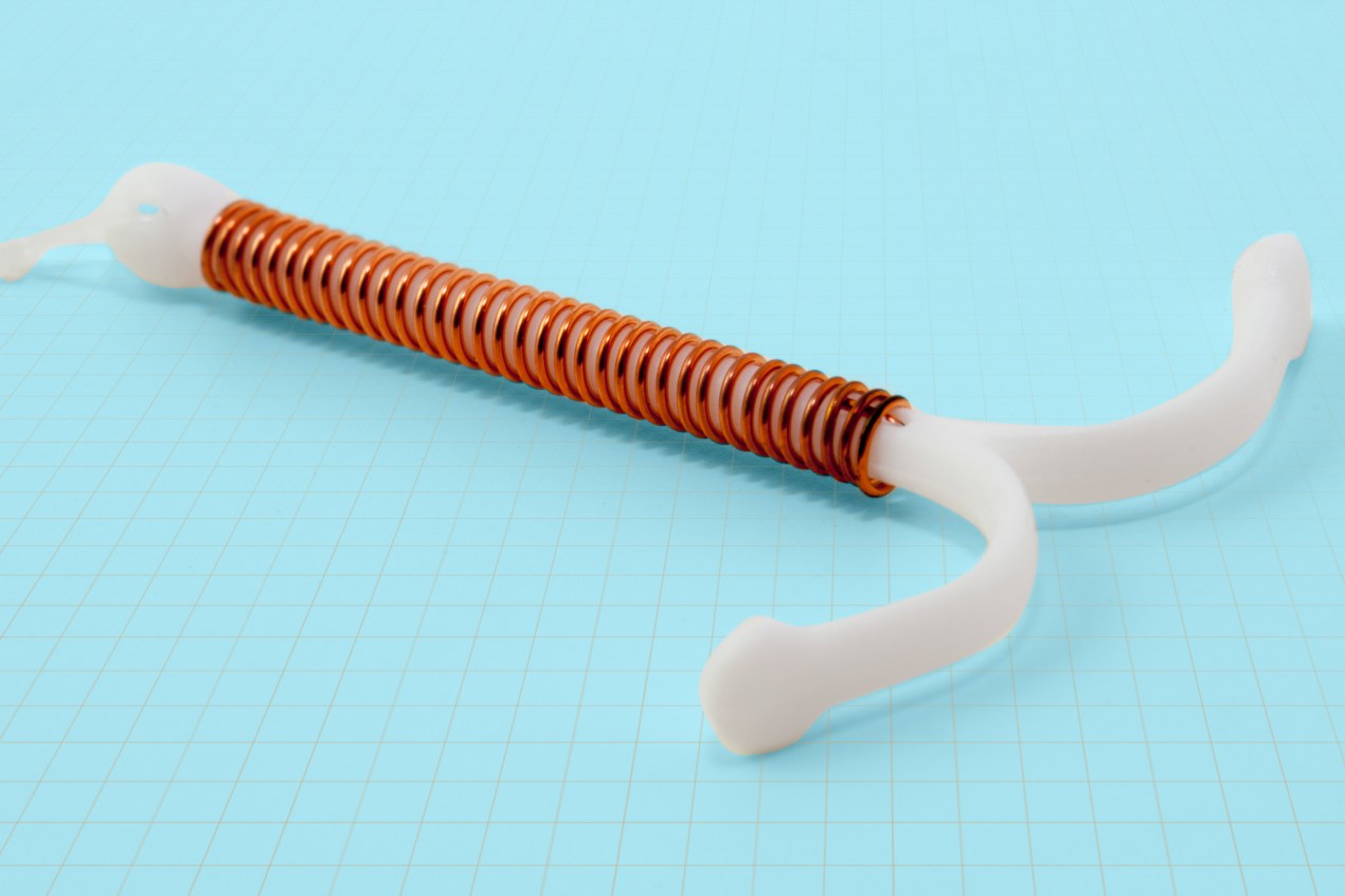 A photo shows an IUD resting on a surface decorated with a grid pattern.