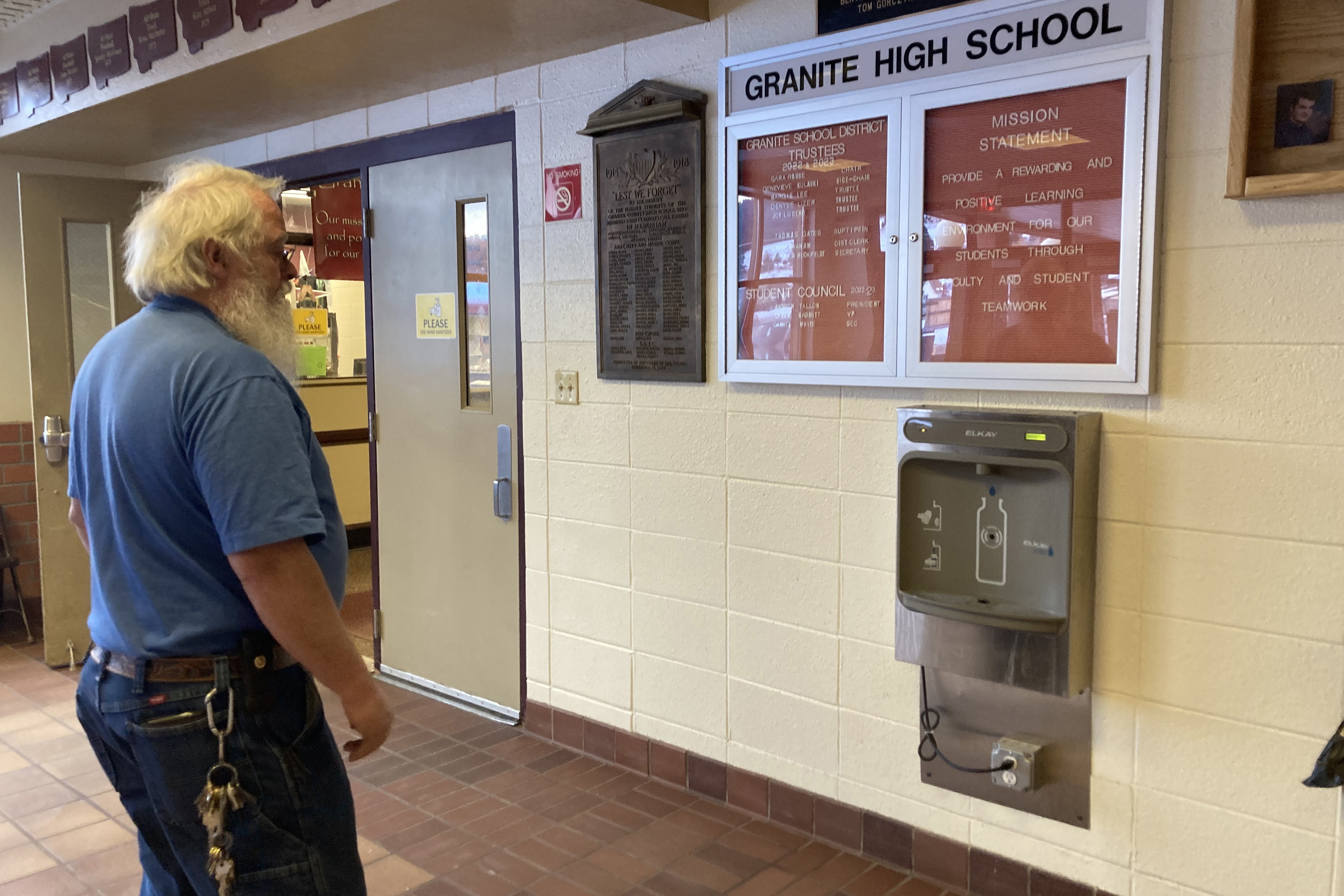 Chris Cornelius stands in front of a filtered water bottle station in a school hallway.