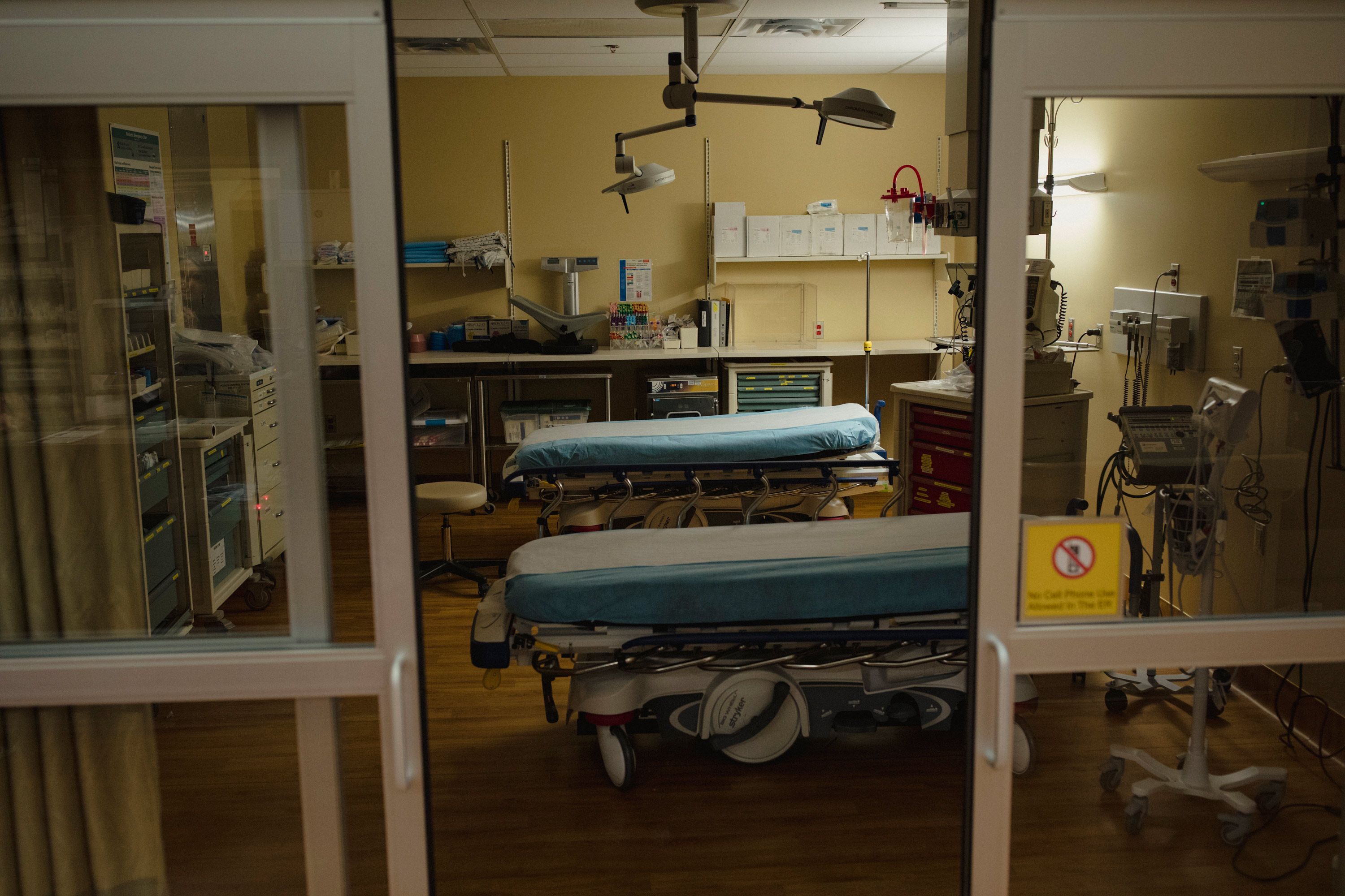 A photo shows a dim room in a hospital with two empty examination tables.