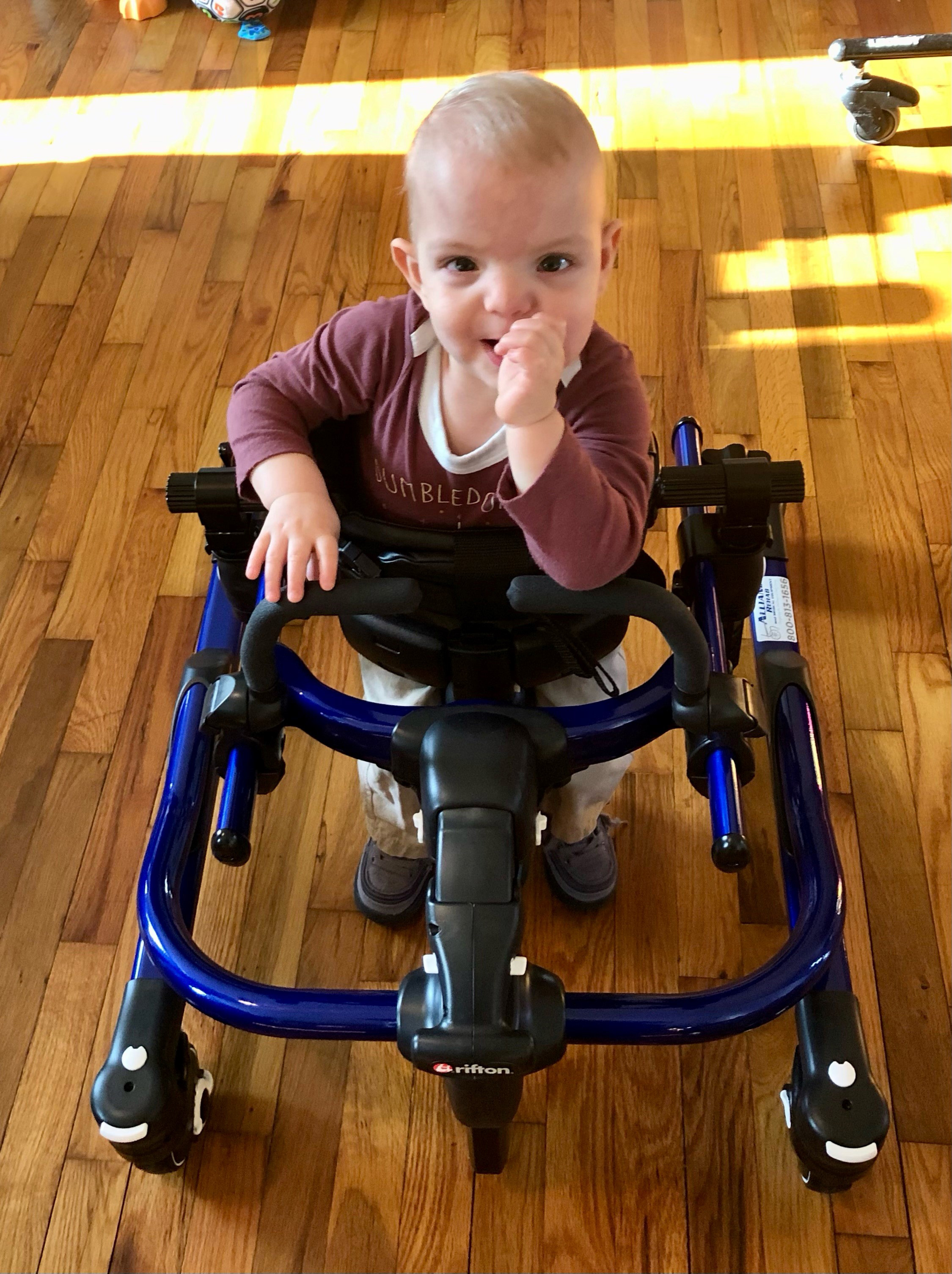 A photo of a two-year-old boy with spina bifida in a walker.